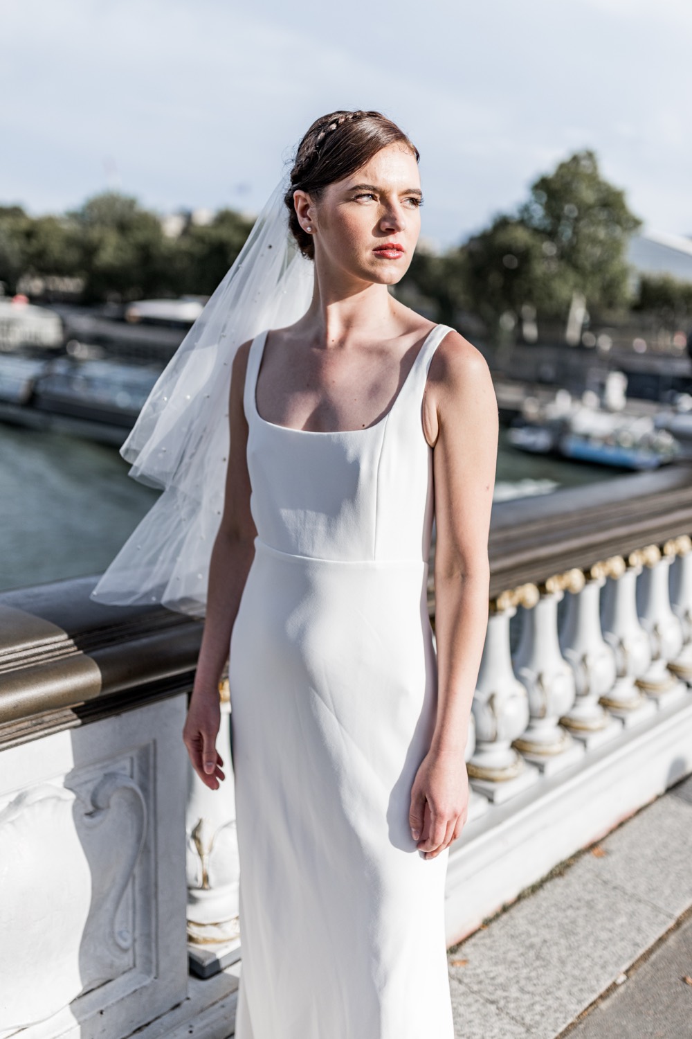 Braut im Säulenkleid mit Schleier auf einer Pariser Brücke